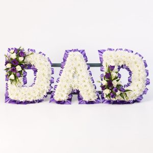 A mass of white double spray chrysanthemums is finished with delicate sprays of roses and lisianthus in white and purple to create this Dad tribute. Our Floral designers can create alternative letters and names